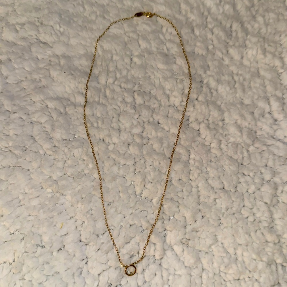 Dainty gold necklace with simple circle and singular diamond.